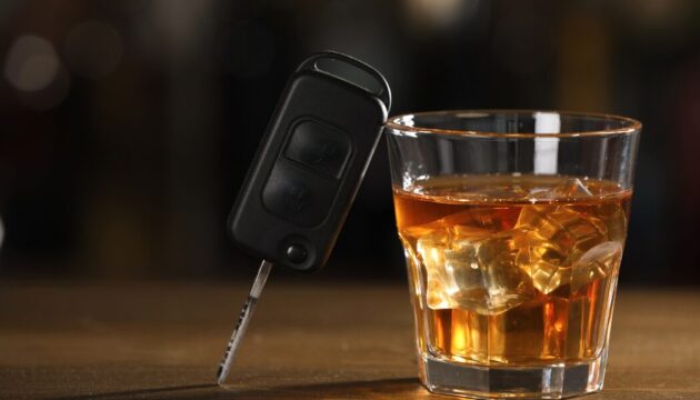Car key next to a glass of whiskey with ice, symbolizing the dangers of drinking and driving in the context of DUI charges in Indiana.